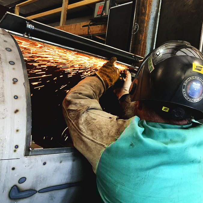 Man using grinder wearing welding hood and PPE