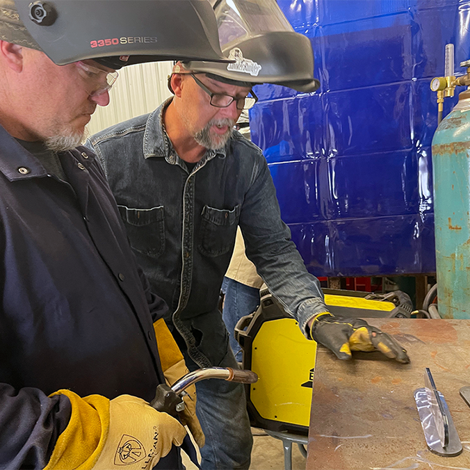 a man teaching a student how to weld in a welding shop