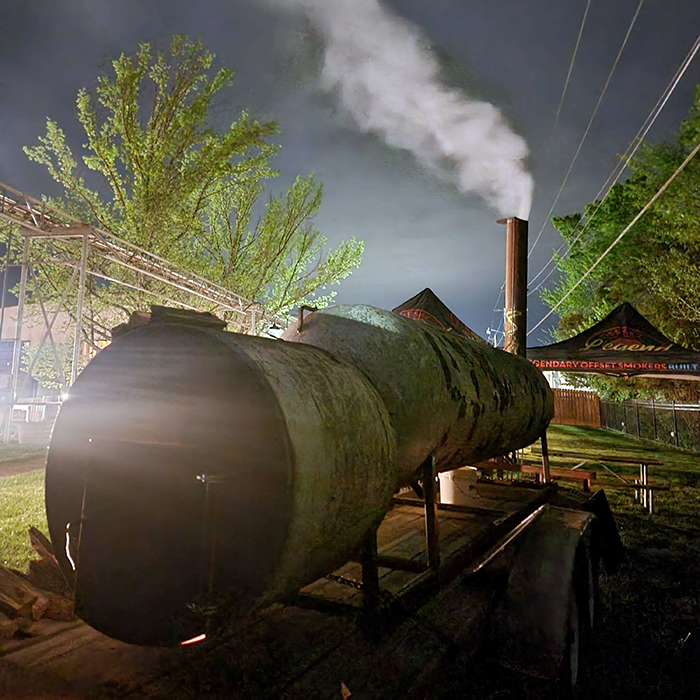 a large meat smoker at night with smoke coming out of the smoke stack
